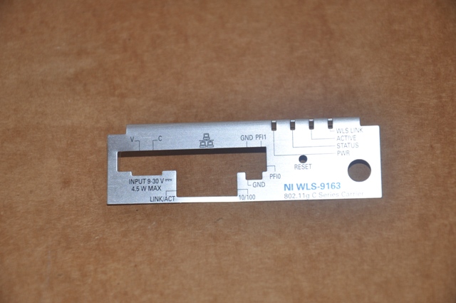 WLS-9163 wireless C-series sleeve kommunikációs hálózati eszköz csatlakozó felületének alumínium burkolata. A WLS-9163 hálózati eszköz a C sorozatú mérőmodulok hordozója. Több mint 50 féle modul használatára alkalmas, amelyek rendelkeznek a szenzorok közvetlen csatlakoztatási lehetőségével a különböző mérésekhez, úgymint elektromos, fizikai, mechanikai és akusztikai. A mérőmodulok jeleit továbbítja az adatokat feldolgozó PC-hez. Az adattovábbítást IEEE 802.11b/g (Wi-Fi) vezeték nélküli kommunikációs interfészen és/vagy a 10/100BASE-T/X Ethernet csatlakozási felületen valósítja meg. A lapon kialakításra került nyílások a csatlakozókhoz való hozzáférést biztosítják. Továbbá a lapon szerepelnek a csatlakozási pontok, működési információk típusonkénti jelölései, amik a helyes csatlakoztatáshoz és működéshez nyújtanak információt. Az alumínium lap egyik oldala ragasztóanyaggal bevont és áttetsző fóliával borított, a másik oldalán pedig információt tartalmazó feliratok láthatók.