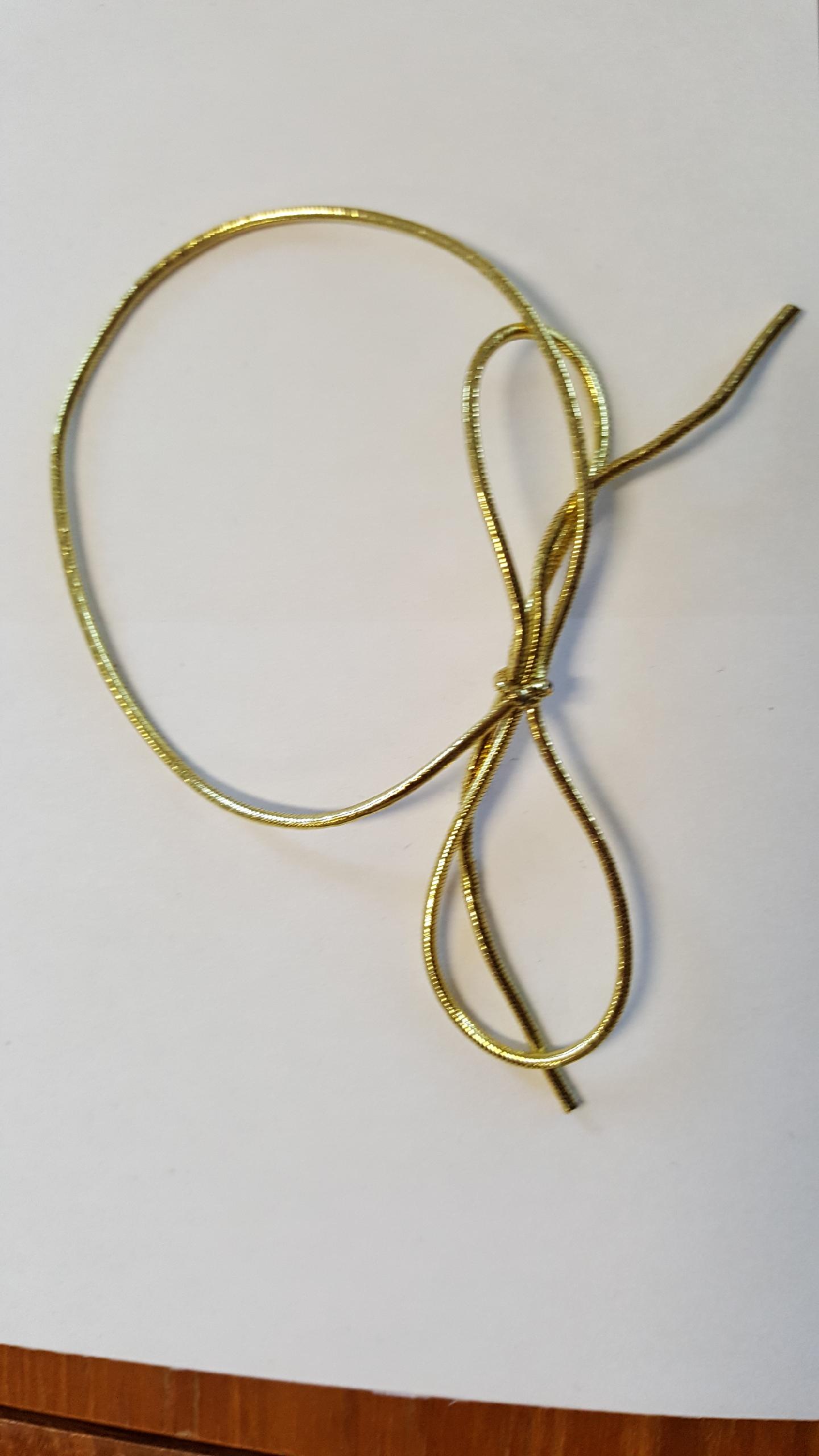 ELASTIC BOW.
USED TO DECORATE A CHOCOLATE BOX.
MADE OF 75% SYNTHETIC RUBBER COVERED WITH 25% METALLIC YARN.
THE PRODUCT IS A CORD OF RUBBER ON THE INSIDE COVERED WITH METALLIC YARN.