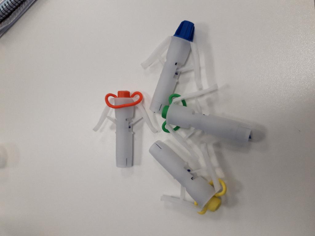 CLAMPEX AUTOMATED PERITONEAL DIALYSIS O-RING.
IT IS USED TO PIERCE A HOLE IN A DIALYSES BAG TO ALLOW THE FLOW OF SOLUTION INTO THE PATIENT.
IT CONSISTS OF A PLASTIC/RUBBER PULL RING, A PLASTIC FLANGE WHICH IS POINTED AT ONE END AND IS SURROUNDED BY AN OUTER SHELL WHICH HAS WINGS ON EACH SIDE, AND AN O-RING. THE PULL RING IS REMOVED SO THAT A TUBE WHICH CARRIES FLUID TO THE PATIENT CAN BE FITTED TO THE DEVICE.  THE WINGS ON THE OUTER SHEEL ARE FIXED IN SUCH A WAY THAT WHEN THEY ARE SQUEEZED, THE WINGS PUSH DOWN THE FLANGE SO THAT THE POINTED END PIERCES THE BAG CONTAINING THE DIALYSIS SOLUTION.
THE DEVICE IS MAINLY MADE OF PLASTIC.