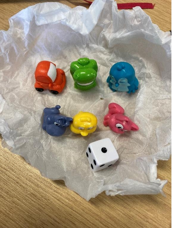 Parts for use in a board game described as:
6 x plastic tokens of various colours
1 x white dice 
All are presented together in one bag.