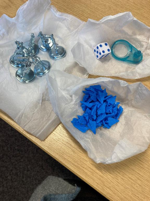 PARTS FOR USE IN A BOARD GAME DESCRIBED AS: 6 x BLUE ZINC MOVERS, 44 x BLUE SHIP TOKENS, 1 x  CLEAR TOKEN AND 1 X CLEAR BASE AND  1 x  16M WHITE DICE WITH BLUE PIPS. ALL ARE PRESENTED TOGETHER IN ONE BAG.