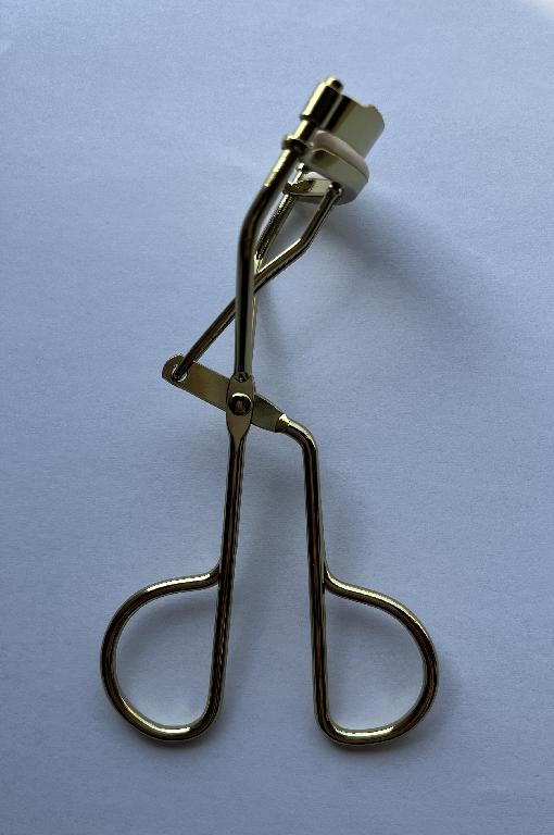 EYE LASH CURLER.  THE BODY OF THE CURLER IS COMPOSED OF CARBON STEEL. THE PART THAT CONTACTS THE EYELASH TO CURL IS ALSO COMPOSED OF CARBON STEEL ON THE TOP WITH A RUBBER INSERT ON THE BOTTOM.