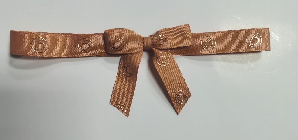 Two strips of grosgrain textile material cut to a specified length, then attached by a short strip of elastic, then tied in a bow with a knot so that the loop is a specified diameter, with bow span and tail ends of a specified length.  This is a made up decorative item for packaging.  The completed item is imported in this manner.
Woven from PET polyester thread.