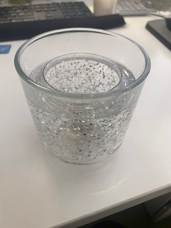 Glass LED candle holder
Glass tumbler, filled with gel and LED lights 
Also contains 2 x CR2450 batteries
The LED lights come on when exposed to heat. 
Function is that this will hold candles and light up when candle is burned, but will be sold separate to the candles themselves.