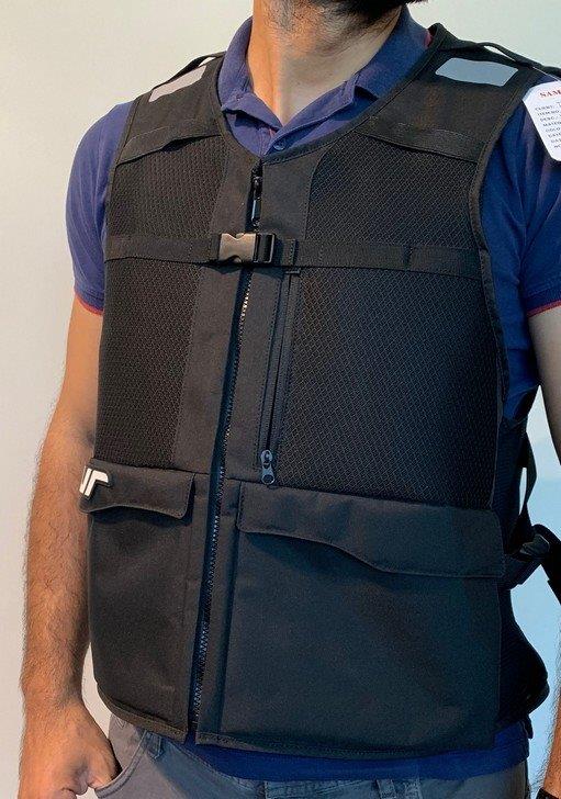CAPO DI MAGLIERIA IN TINTA UNITA DI FIBRE SINTETICHE SENZA MANICHE  A FORMA DI  GILE', CHE COPRE LA PARTE SUPERIORE DEL CORPO.  LA PARTE POSTERIORE SI PRESENTA COME UNO ZAINO, PARTE INTEGRANTE DEL CAPO.
IL CAPO, UTILIZZATO PREVALENTEMENTE DAI  MOTOCICLISTI, E'  DESTINATO AD ESSERE INDOSSATO SOPRA ALTRI INDUMENTI .
LA PARTE ANTERIORE  DEL GILE'  PRESENTA UN'APERTURA COMPLETA CHE SI CHIUDE CON CERNIERA,  DUE GRANDI TASCHE E  UNA TASCA A FILETTO CHIUSA DA CERNIERA. IL GILE' ALL'INTERNO E' DOTATO DI UNA  CINTURA  CON CHIUSURA A VELCRO CHE REGOLA L'ADERENZA AL CORPO DELLA PARTE  POSTERIORE DEL CAPO/ZAINO.