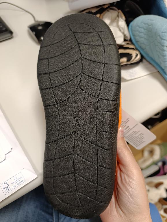 Pantofola con tomaia in materiale tessile arancione, a maglia, con finitura in microfibra e sottopiede in materiale tessile.
La suola è composta da materiale tessile supportato da uno strato di gomma in cui è integrato in modo da non poter essere staccato.