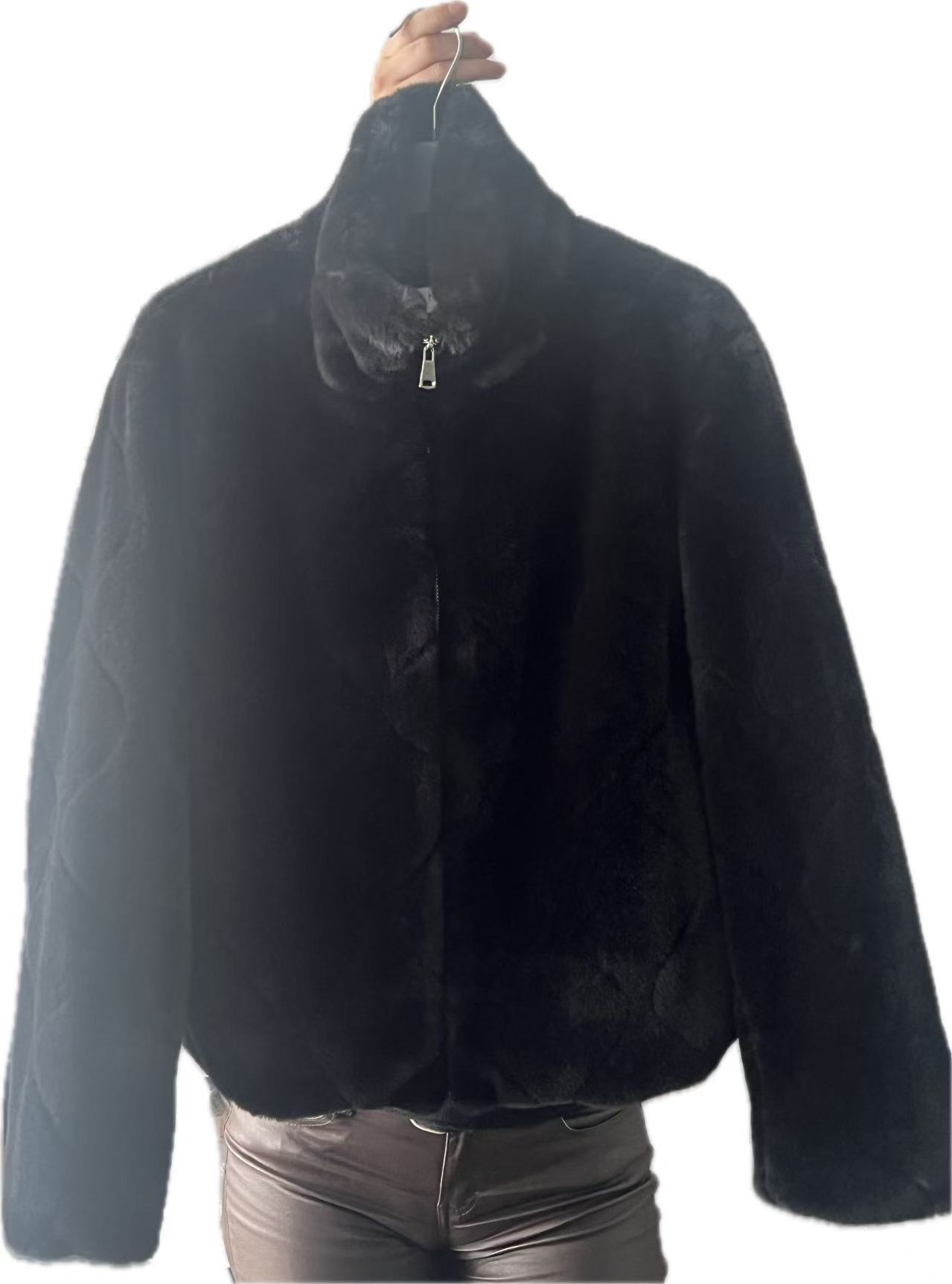 Giubbino da donna in pelliccia artificiale, di colore nero, la cui superficie è costituita da un tessuto a maglia sintetica con un’imitazione della pelliccia incollata e/o cucita ad essa. Copre fino alla vita, a maniche lunghe.