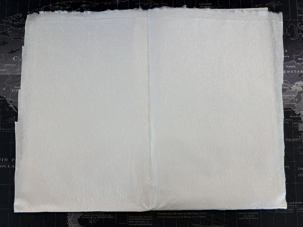 Materiale assorbente disponibile sia in bobine sia in fogli pretagliati, con dimensioni variabili a seconda delle esigenze del confezionamento. Le bobine presentano una larghezza compresa tra 60 mm e 1800 mm, mentre la lunghezza può variare liberamente in base ai processi produttivi. I fogli, invece, sono disponibili in un ampio ventaglio di formati, che vanno dai più piccoli 50 × 70 mm fino ai più grandi 900 × 2400 mm, o 1200 × 350 mm, per adattarsi a diversi tipi di vassoi e applicazioni.
La funzione principale di questo materiale è quella di agire come pad assorbente all’interno dei vassoi destinati al confezionamento di alimenti freschi. Il pad è progettato per assorbire i liquidi rilasciati dagli alimenti durante la conservazione, contribuendo a mantenere il prodotto confezionato più asciutto, igienico e visivamente più gradevole. Questo migliora la qualità percepita dal consumatore e aiuta a prolungare la shelf‑life degli alimenti freschi.
Dal punto di vista strutturale, il pad assorbente è un materiale multistrato composto da uno strato di film plastico accoppiato, tramite colla hot‑melt, a uno strato di tessuto non tessuto airlaid. Quest’ultimo è costituito da una miscela di fibre di cellulosa e fibre sintetiche, progettate per garantire un'elevata capacità assorbente mantenendo al tempo stesso integrità meccanica e maneggevolezza.
Le analisi effettuate sul campione mostrano che il tessuto non tessuto è composto per l’89,6% da fibre di cellulosa e per il 10,4% da fibre sintetiche in polietilene. Nel manufatto finito, il tessuto non tessuto rappresenta l’82,6% della struttura complessiva, mentre la pellicola polimerica costituisce il restante 17,4%. La massa areica del prodotto è pari a 75,19 g/m², valore che riflette un equilibrato rapporto tra capacità assorbente e resistenza del materiale.
Nel complesso, si tratta di un prodotto specificamente progettato per l’industria del confezionamento alimentare, ampiamente utilizzato per garantire condizioni igieniche ottimali e migliorare la presentazione degli alimenti freschi venduti in vaschette