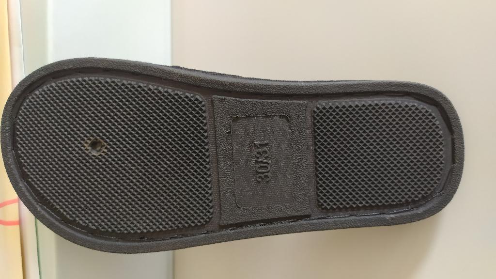 Pantofola da bambino, con tomaia in materiale tessile con motivi geometrici di colore rosso e nero ed una fascia effetto peluche di colore grigio.
La suola è composta da materiale tessile supportato da uno strato di gomma in cui è integrato in modo da non poter essere staccato.
L’intersuola è costituita da materiale polimerico, non è removibile ed è foderata dalla parte a contatto con il piede, con materiale tessile.Suola esterna in materiale tessile.
