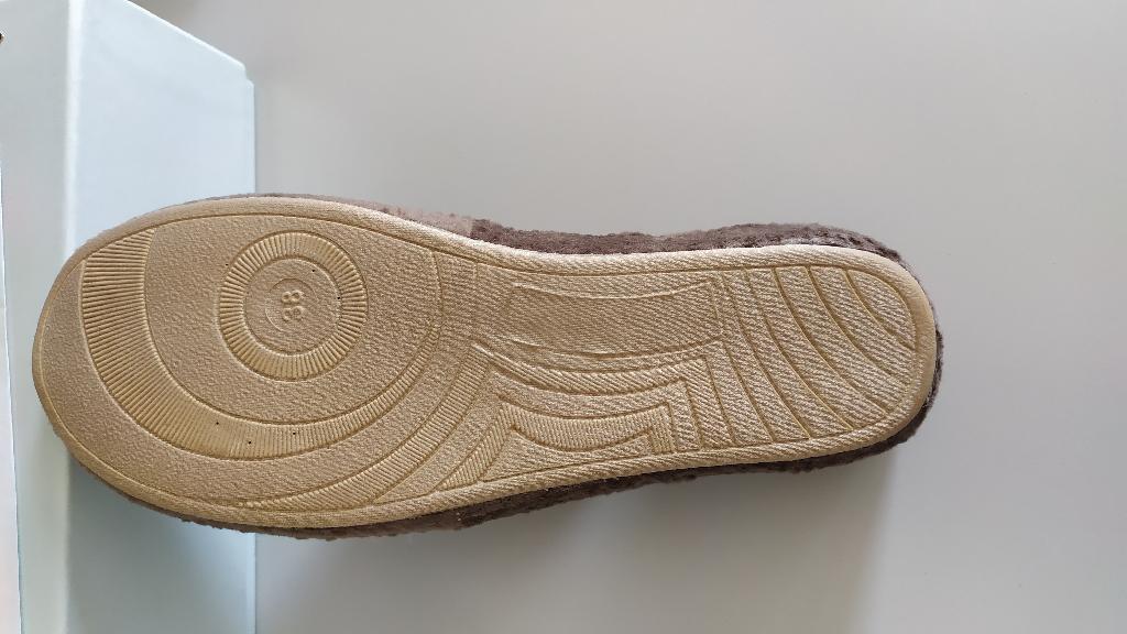 Pantofola da camera con tomaia di materiale tessile e suola esterna di materiale tessile. Lo strato esterno è costituito da tessuto ad effetto vellutato, lo strato interno è invece costituito da tessuto a maglia i due strati sono separati da una doppia imbottitura. La suola è costituita da materiale tessile integrato con materiale polimerico in modo tale che i singoli costituenti non possano essere separati. L’intersuola è costituita da materiale polimerico, non è removibile ed è foderata dalla parte a contatto con il piede, con materiale tessile
.