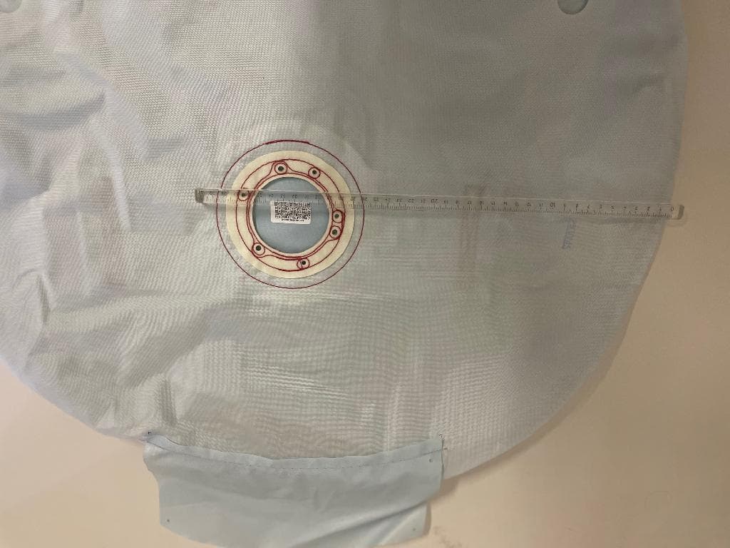 Componente di un sistema di airbag per auto consistente in un cuscino gonfiabile di sicurezza. L’articolo si presenta piatto e circolare (con diametro di circa 67 cm)  in tessuto di Nylon ad alta resistenza, di colore celeste, con una cucitura rettangolare nella parte posteriore e rinforzo centrale nella parte anteriore. All’estremità è cucita un'aletta rettangolare di circa 10 cm.