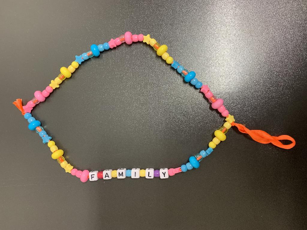 Braccialetto di fantasia composto da perline in plastica di vari colori. L’articolo è utilizzato come porta cellulare.