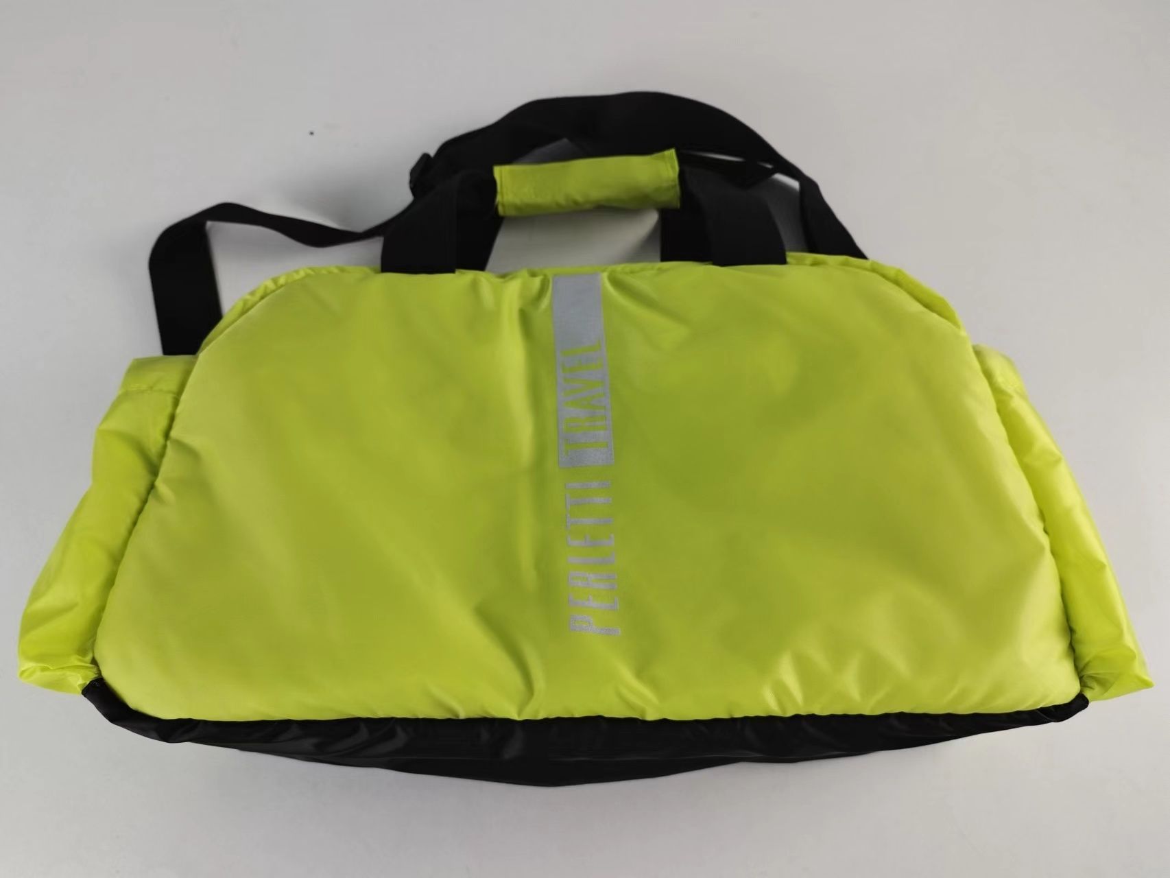 Borsa da viaggio. Sulla base di quanto dichiarato, l'articolo presenta una superficie esterna in tessuto di nylon di colorazione dal giallo al verde fluorescente con dettagli neri. L'interno è in tessuto ed è dotato di un divisorio e di una taschina con cerniera in tessuto a rete. Il prodotto presenta una chiusura con zip. È munito di tracolla regolabile ai lati e di due manici in tessuto.