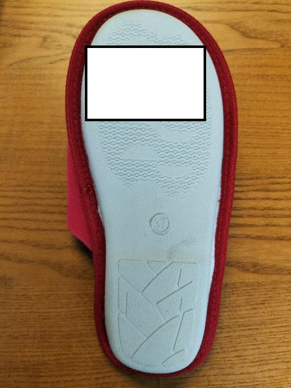 Pantofola da donna.
La tomaia, leggermente imbottita, è costituita da materiale tessile (poliestere) simil velluto ed è decorata con un pupazzetto raffigurante l'omino di pan di zenzero, applicato mediante cucitura. La suola esterna presenta rilievi antiscivolo ed è costituita interamente da gomma.
L’intersuola, costituita da materiale polimerico, non è removibile ed è foderata dalla parte a contatto con il piede, con materiale tessile.