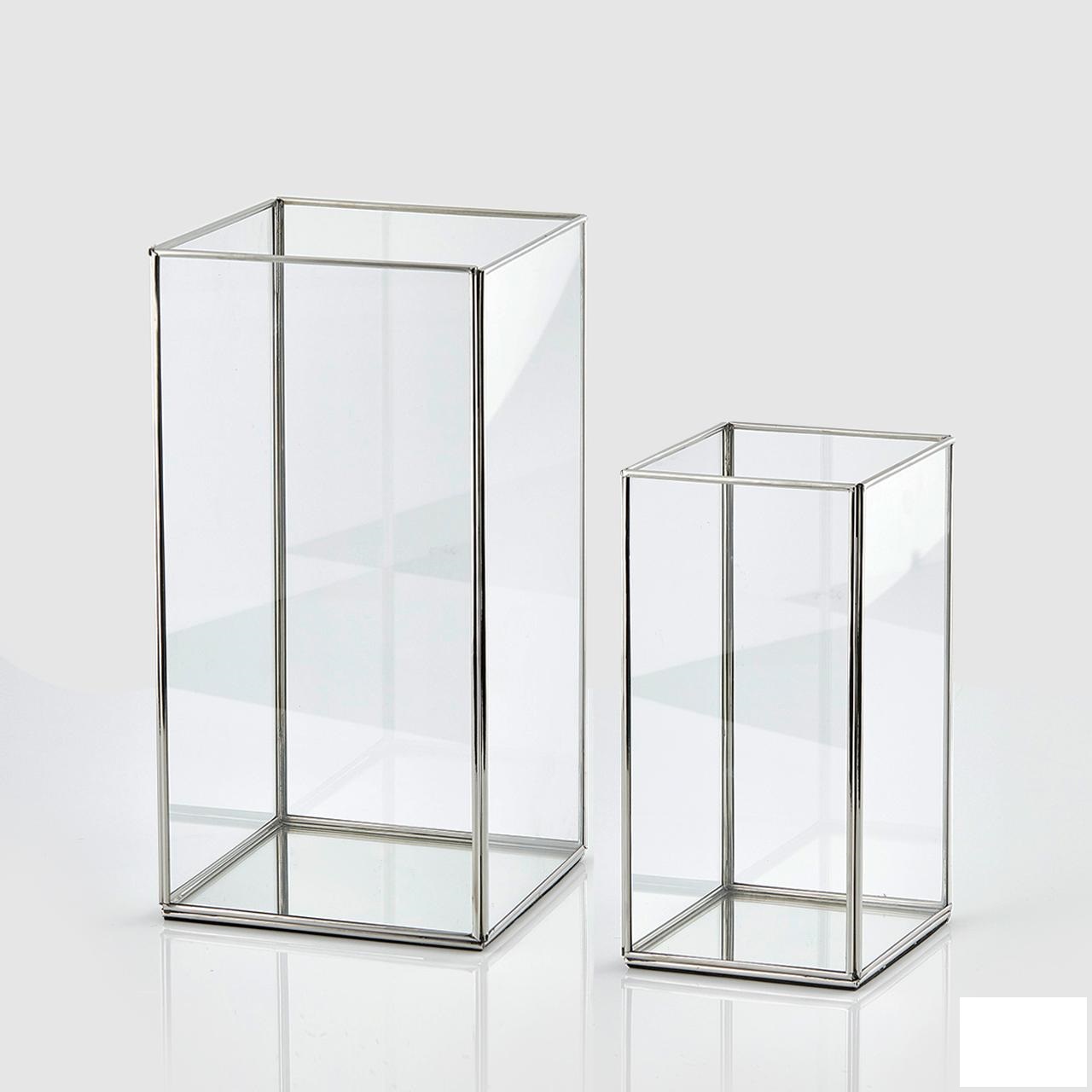 Lanterna in vetro, con profili in metallo comune, avente forma di parallelepipedo aperto sopra.
La merce si presenta confezionata in una scatola di cartone contenente due pezzi aventi le seguenti dimensioni 21x21xh40cm  e 16x16xh30cm.