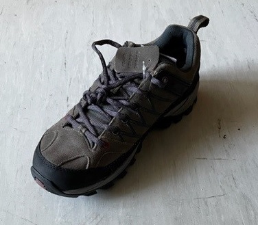 Calzatura da trekking per uomo con suola esterna di gomma sintetica bicolore, con rilievi antiscivolo su tutta la lunghezza. La tomaia è costituita prevalentemente da cuoio e in misura minore da tessuto e gomma. La calzatura è munita di un'intersuola amovibile foderata di tessuto nella parte a contatto con il piede e di un sistema di chiusura tradizionale per allacciatura.