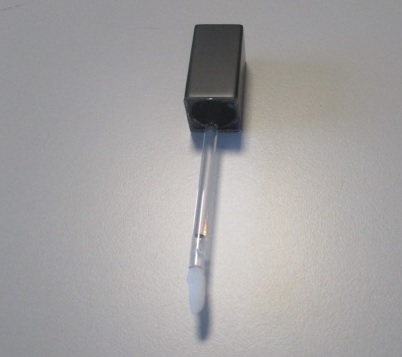 Applicatore per prodotti cosmetici.
Il prodotto è composto da un'asta montata su un cappuccio di sezione quadrata in plastica ricoperta da un sottile foglio in alluminio di colore nero, alla cui estremità è presente un pennellino in spugna sintetica.
L'applicatore è progettato per applicare prodotti cosmetici  (gloss) sulle labbra.