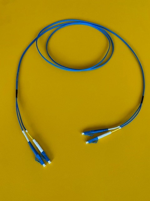 Cavo in fibra ottica di tipo monomodale 9/125 (ove il numero "9"  indica il diametro in micron del nucleo della fibra e il numero "125" indica il diametro, sempre in micron, del mantello di protezione del nucleo) composto da due fibre di vetro (duplex) G652 e G657 rivestite individualmente con rivestimento primario da 250 micron e con una guaina protettiva in materiale termoplastico colorato secondo lo standard internazionale TIA/EIA, munite ad entrambe le estremità di connettori operativi di tipo LC .
Il cavo può essere fornito con guaina esterna in due diverse colorazioni, blu e giallo.
Ogni cavo è singolarmente confezionato in una busta trasparente ed è provvisto di relativo test report a comprova del perfetto funzionamento del prodotto e della sua aderenza agli standard tecnico/normativi.
Il cavo può essere di diverse lunghezze, a partire da 0,5 m fino a 60 m.
Questo tipo di cavo consente di trasmettere segnali ottici collegando apparecchiature di telecomunicazioni, trasmissione dati, FTTH (Fiber To The Home) ed IT (Information Technology).