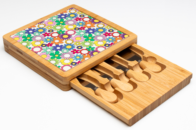 Assortimento condizionato per la vendita al dettaglio all'interno di scatola in cartone, dimensioni 24,5 x 24,5 x 6 cm. composto da: 
- un tagliere quadrato in legno di bambù 23 x 23 x 5 cm., con incavi in cui sono posizionati n. 4 coltellini tagliagrana di dimensioni 11,5 x 3 x 1,8 cm, con manico in legno di bambù e lama in acciaio inossidabile; 
- una piastrella in ceramica 20 x 20 cm, su cui è stampato un disegno floreale.
Il prodotto è destinato alla tavola di casa o alla cucina.