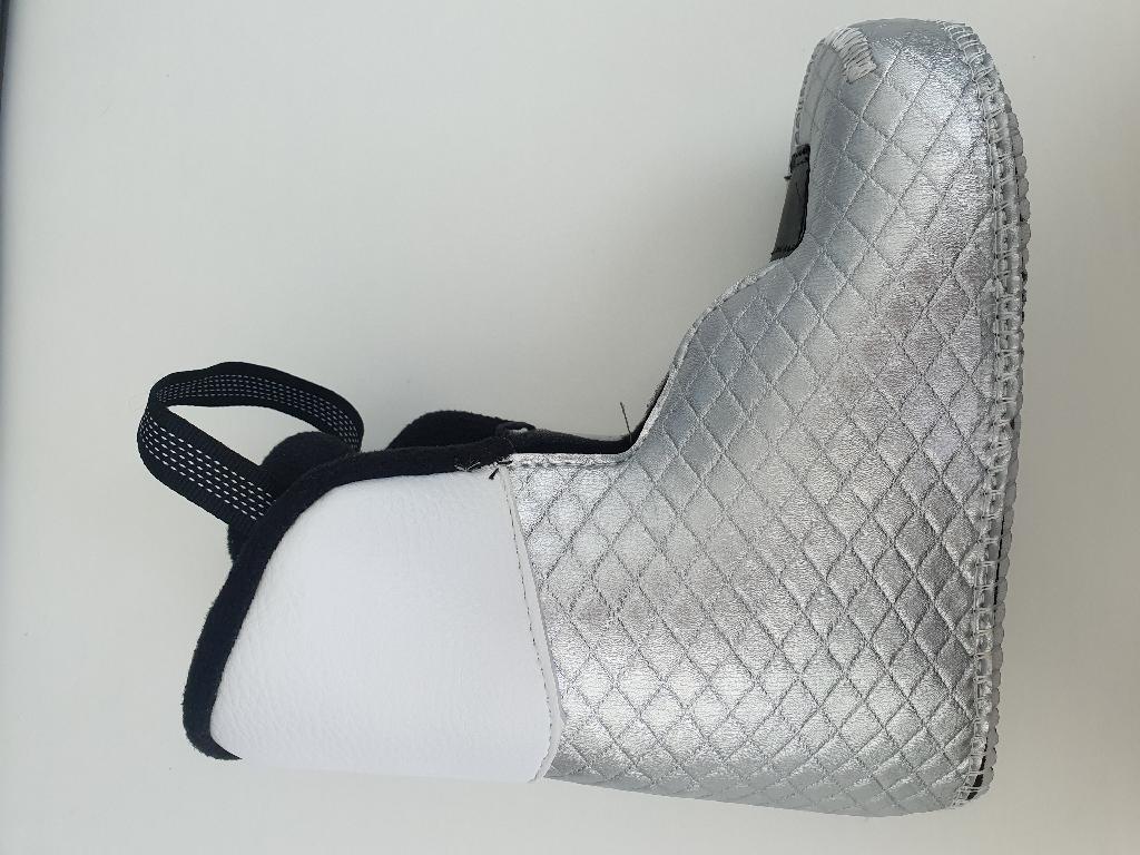 Scarpetta interna di colore di bianco e argento da inserire dentro lo scafo in plastica di uno scarpone da sci.
Il materiale di cui è composta è tessile con parti di materia plastica, elastico e fettuccia.