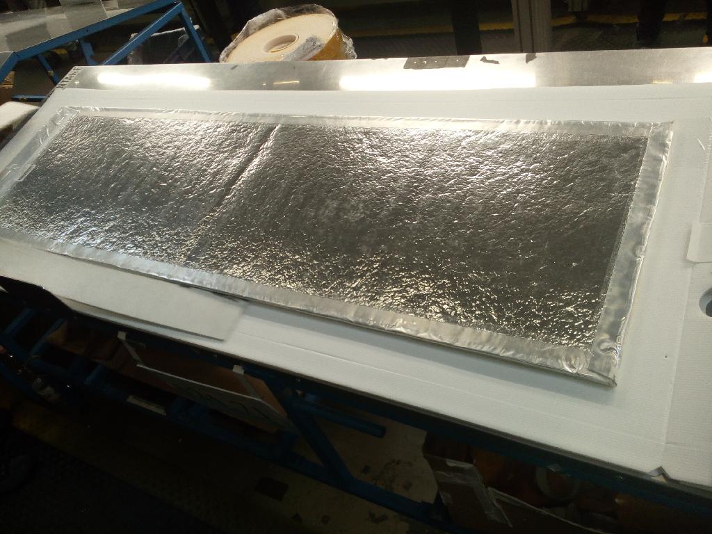 Pannello sottovuoto di fibra di vetro bianca. La merce si presenta sotto forma di lastra rigida di forma rettangolare, di spessore di circa 2 cm e colore bianco, chiusa all’interno di una busta di plastica argentata sigillata. 
L'oggetto è composto da materiale lanuginoso caratterizzato da fibre riconducibili al vetro.
La merce è destinata ad essere montata nel telaio laterale di un frigorifero e fungere da isolante.
Dimensioni variabili: fino a circa 1,5 m di lunghezza, 0,5 di larghezza.