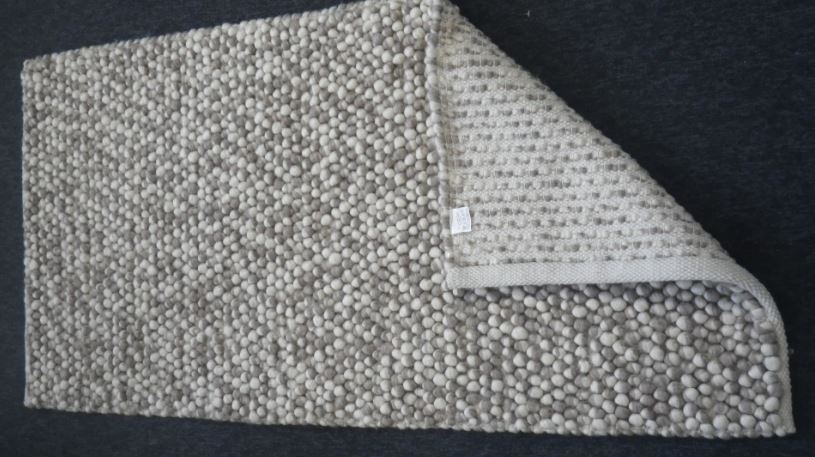 Taisnstūra formas austs paklājs no vilnas (80 %) un kokvilnas (20 %). Izmēri 70 x 140 cm. Šaurākās malas ir nolocītas un nošūtas. Paklājā ir ieausti vilnas pavedienu kūlīši, no kuriem paklāja virspusē izveidoti bumbuļveidīgi pacēlumi.