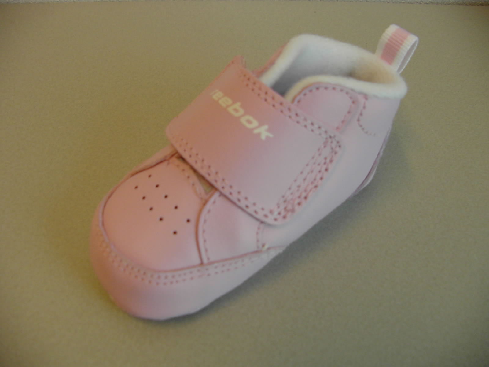 Huisschoeisel voor baby's geheel van leder met de volgende kenmerken:
- de enkel bedekkend;
- voorzien van klittenbandsluiting;
- een tong van kunststof;
- op de hiel een aantreklus van textiel;
- aan de buitenzijde en op de wreef zijn ventilatie gaatjes aangebracht;
- aan de buitenzijde van het schoentje en op het zooltje staat het logo afgebeeld;
- op de klittenbandsluiting en op het zooltje staat de merknaam vermeld;
- heeft een uitneembaar binnenzooltje.