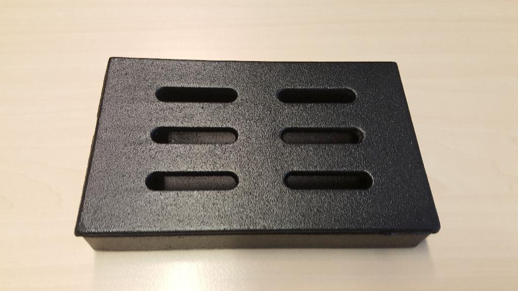 Een zogenoemde smoker box met -volgens opgave- onder andere de volgende uiterlijke en technische kenmerken:
- bestemd om te worden gevuld met hout(snippers) voor het roken van voedsel en geschikt om te worden geplaatst
  op bijvoorbeeld een barbecue of grill;
- vervaardigd van gietijzer in een rechthoekige vorm met de afmetingen van ongeveer 20,5 x 12,5 x 3,5 cm;
- niet voorzien van een eigen verwarmingsinrichting;
- met een afneembaar deksel voorzien van 6 openingen.