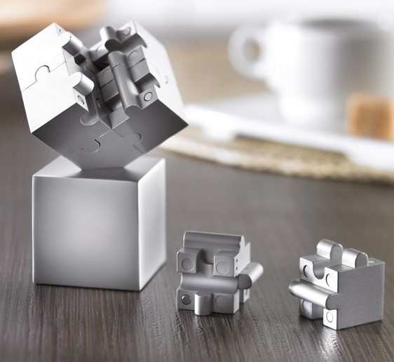Een presse-papier met onder andere de volgende kenmerken:
- bestemd om te worden verkocht als relatiegeschenk en om te worden gebruikt als presse-papier;
- vervaardigd van onedel metaal;
- 8 zware, magnetische puzzelstukjes in de vorm van een kubus; 
- afmetingen van 3,7 x 3,7 x 3,7 cm;
- een hol voetstuk in de vorm van een kubus;
- een 3-hoekige inkeping aan de bovenzijde waarin de kubus van puzzelstukjes geplaatst kan worden;
- afmetingen van 3,6 x 3,6 x 3,6 cm.