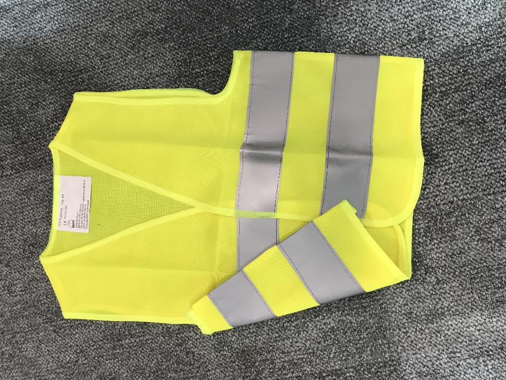 Een veiligheidsvest met –volgens opgave– onder andere de volgende kenmerken:
- voor kinderen, om goed zichtbaar te zijn in bijvoorbeeld het verkeer;
- een geconfectioneerd artikel in de vorm van een mouwloos vest, gebreid, van 100% polyester;
- 2 horizontale reflecterende stroken met een breedte van ongeveer 5 cm;
- aan de voorzijde een klittenbandsluiting, links over rechts;
- een V-vormig halsopening;
- afgebiesde randen;
- afmetingen van ongeveer45 x 40 cm.