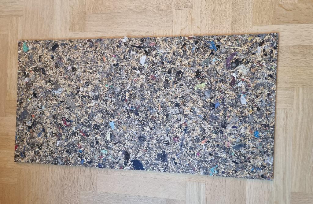 Een zogenoemd textiel paneel met -volgens opgave- onder andere de volgende kenmerken en eigenschappen:
- voor gebruik bij de bouw en voor interieurtoepassingen;
-- vervaardigd door het warmpersen van fijngemalen mammoetgras en polyestertextielvezels in de vorm van een onbuigzaam harde plaat;
- de polystervezels zijn afkomstig van verschillende kleuren snijafval van de textielindustrie;
- bestaande uit 90% gemixte kleuren textiel vezels van polyester en 10% mammoet gras;
- afmetingen van 2440 mm x 1830 mm x 8 mm en 2440 mm x 1830 mm x 14 mm.