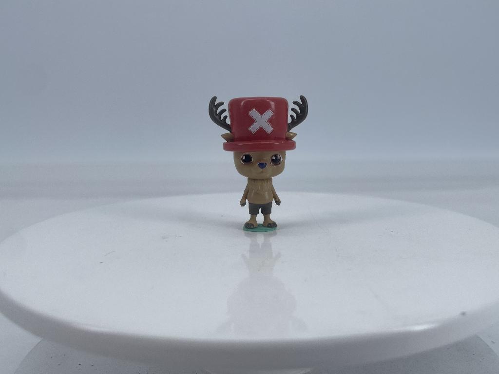 Een speelgoedfiguur met -volgens opgave- onder andere de volgende kenmerken:
- voor het vermaak van kinderen;
- een niet-menselijk wezen uit 2 televisieseries;
- alle figuren staan recht op, niet buigzaam en hebben 2 armen, 2 handen, 2 benen en 2 voeten;
- de hoofden hebben verschillende uitvoeringen (zie afbeeldingen):
-- een dierenhoofd met een hoed, oren en een gewei;
-- een hoofd in de vorm van een openstaande bloem met 5 blaadjes;
-- een zwart hoofd met een neus met een witte driehoek op het voorhoofd en een rode kap;
-- een gerimpeld hoofd zonder neus met duidelijke ogen;
- vervaardigd van gerecycled kunststof;
- een hoogte van ongeveer 4 cm.

Elk figuurtje wordt blind verpakt in een bedrukte, verzegelde en ondoorzichtige papieren zak.