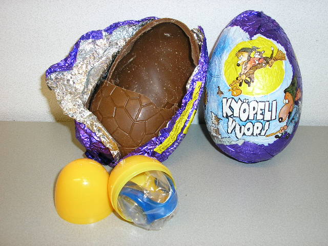 Een samengesteld product op basis van melkchocolade, bestaande uit een eivormige schil van melkchocolade bevattende een capsule van kunststof met daarin speelgoed als verrassing. Het chocolade ei heeft een gewicht van ongeveer 100 gram en de capsule heeft een gewicht van ongeveer 15 gram. Het ei is verpakt in gekleurd aluminium folie en voorzien van een sprookjesvoorstelling.