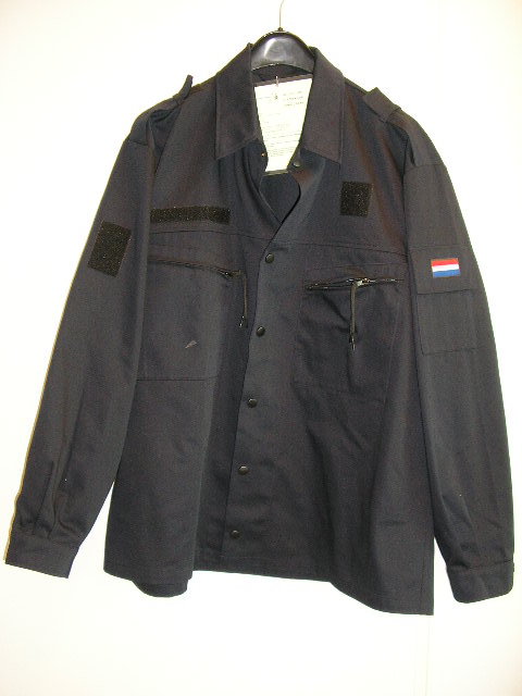 Werkkleding voor militairen zijnde een jas, blauw van kleur, vervaardigd van een stevig en krimpvrij weefsel (65% katoen en 35% polyester) met de volgende kenmerken: 
- een aangezette kraag; 
- lange mouwen, met een gedeeltelijke opening, aan de uiteinden voorzien van drukknopen; 
- een gehele opening aan de voorzijde, voorzien van een drukknoopsluiting; 
- twee zakken aan de voorzijde voorzien van een ritssluiting; 
- op de schouders epauletten voor het aanbrengen van passanten voorzien van klittenband; 
- boven de linker borstzak een vierkante en op de rechter borstzak en rechter mouw een langwerpige voorziening van klittenband; 
- op de linker mouw een pennenzakje met klepsluiting voorzien van klittenband; 
- op de klep van het mouwzakje zijn de kleuren van de nationale vlag verwerkt.