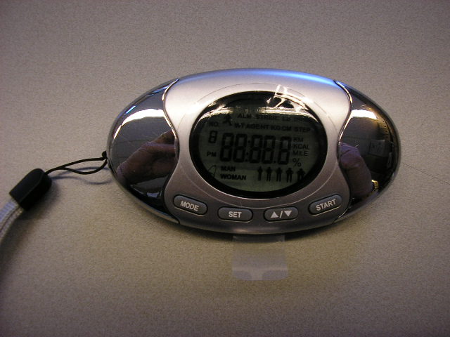 Een gecombineerd apparaat in een kunststof behuizing, met ondermeer de volgende functies en kenmerken:
- klokje met een alarmfunctie in de vorm van een horloge-uurwerk;
- schredenteller (pedometer);
- afstandsteller;
- calorieënteller;
- lichaamsvet meter;    
- viertal functietoetsen aan de voorzijde;
- ovale vorm met afmetingen van ongeveer 9x5 cm;
- voorzien van polsbandje;
- bevestigingsclip voor aan de kleding;
- ovaalvormig display aan de voorzijde;
- werkend op knoopcel batterij CR2025.
Het artikel is verpakt in een kartonnen doosje met een gebruiksaanwijzing.