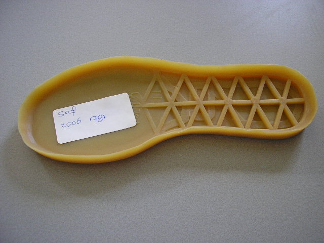 Een losse buitenzool van rubber met een opstaande buitenrand. De buitenzool is deels bekleed met een laagje gebonden textielvlies dat niet de duurzaamheid en/of weerstandsvermogen bezit om als zool van textiel te worden aangemerkt.