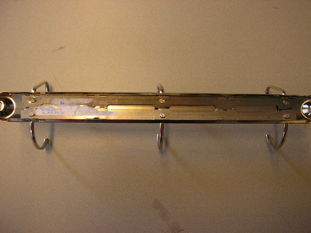 Een ringbandmechanisme voor opbergmappen van onedel metaal met een lengte van ongeveer 28 cm, voorzien van zes armen van staaldraad. De armen zijn aan de onderzijde gemonteerd op twee rechthoekige stalen platen en kunnen worden gesloten door de twee tegenover elkaar liggende armen naar elkaar toe te drukken, waardoor ze drie D vormige ringen vormen. De rechthoekige platen zijn voorzien van vier uitsparingen. De bovenste plaat heeft aan de bovenzijde naast de uitsparingen voor de ringen twee uitsparingen om het mechanisme aan een opbergmap te bevestigen.
