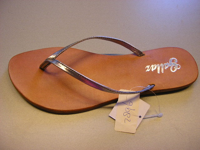 Teenslippers met een bovendeel van kunststof en buitenzool van leder. Het bovendeel bestaat uit een V-vormige band van kunststof, die op drie punten aan de zool is bevestigd. De buitenzool is voorzien van een kunststof hak met de afmetingen van circa 4,5 x 6,5 cm., welke is vastgespijkerd aan de buitenzool.