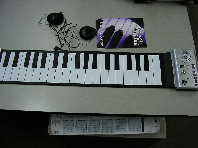 Een oprolbaar elektrisch muziekinstrument zijnde een zogenaamde  piano keyboard,  met ondermeer de volgende kenmerken:
- afmetingen van ongeveer 64x12 cm;
- met 22 witte toetsen en 15 zwarte toetsen;
- aan de rechterzijde is een bedieningspaneel aangebracht voorzien 
  van diverse functie knoppen, twee LED’s en een luidspreker;
- werkend op drie AAA batterijen of via een 6V adapter (niet 
  bijgeleverd);
Het artikel is opgemaakt voor de verkoop in het klein en tezamen verpakt met een hoofdtelefoon en gebruiksaanwijzing.