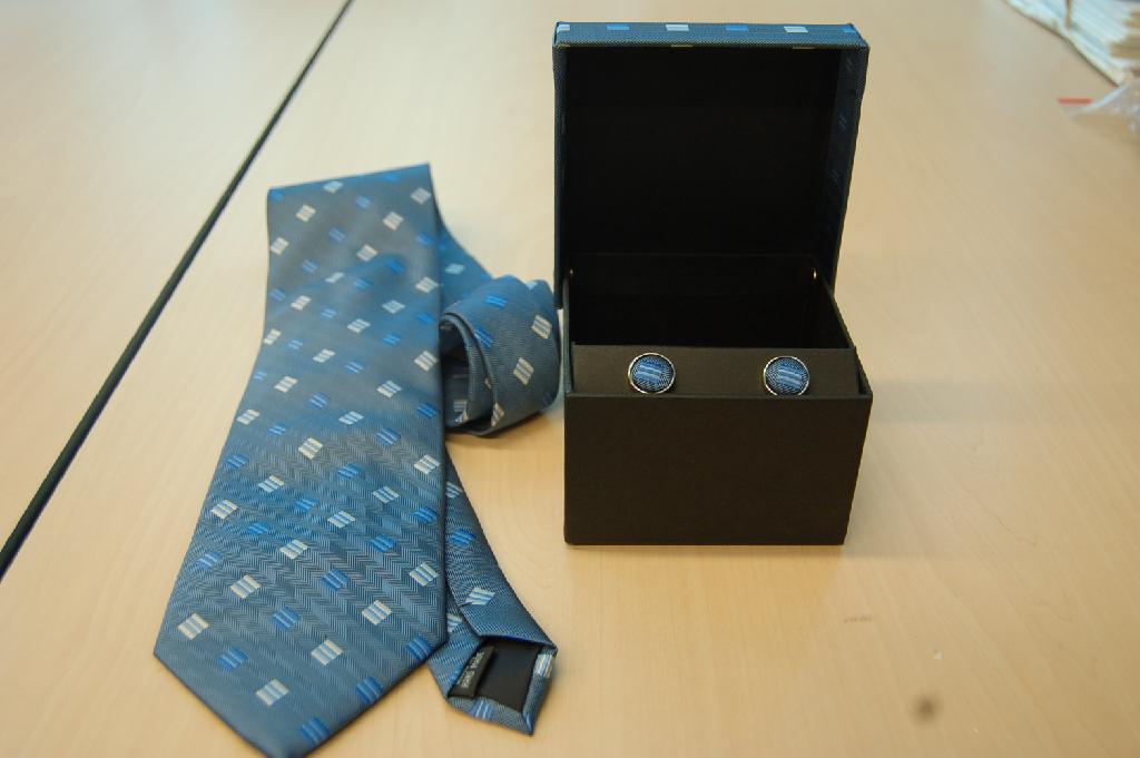 Manchetknopen van onedel metaal, belegd met een strookje textiel. De manchetknopen, zijnde fancybijouterieën, worden tezamen aangeboden met een stropdas van geweven synthetische textiel (polyester) in een doosje van karton met een scharnierend deksel van textiel waarvoor separaat een BTI is afgegeven met referentie NL RTD-2007-003406.