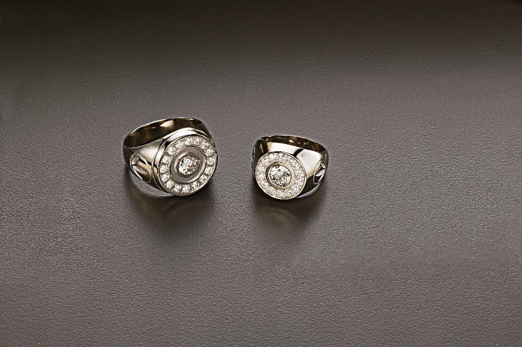 Een 18 karaats wit gouden ring met een zetting van diamanten en een gestyleerd bedrijfslogo, aan weerszijden van de ring.