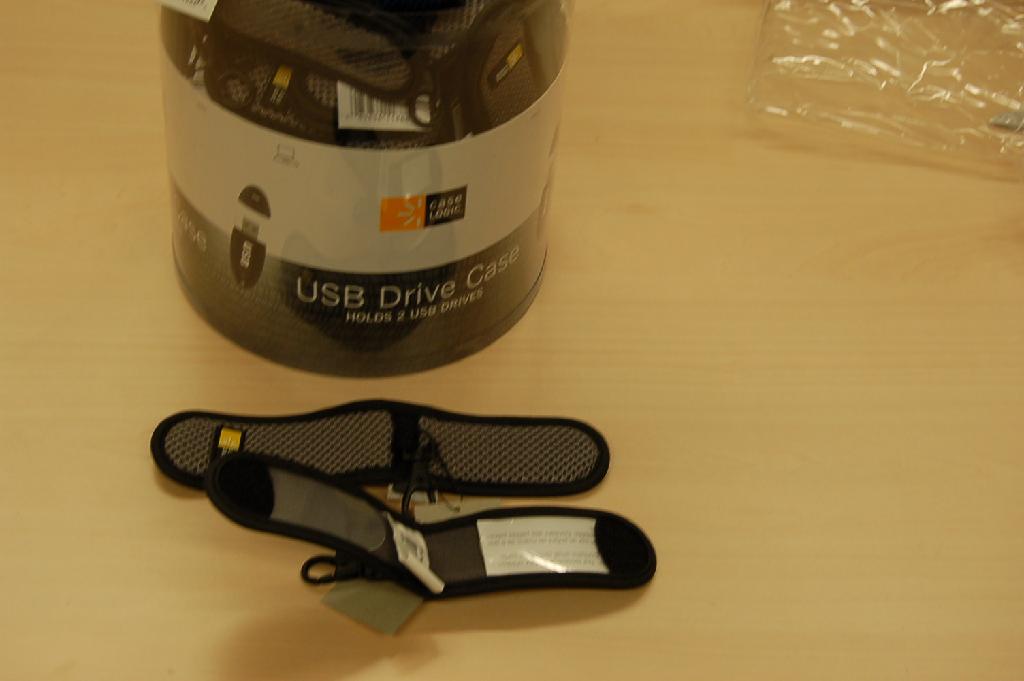 Een opberghoesje voor een USB-stick of een MP3-speler. Het hoesje bestaat uit een strook breiwerk dat aan de randen is afgewerkt met een kunststof bies. Aan de binnenzijde is aan de uiteinden een kunststof plaatje aangebracht waardoor er twee vakjes ontstaan. Op de kunststof plaatjes is klittenband aangebracht en door de hoes dubbel te vouwen wordt de hoes gesloten. Aan de buitenzijde is een logo aangebracht met in het midden een lus van textiel waaraan een kunststof musketonhaakje hangt.