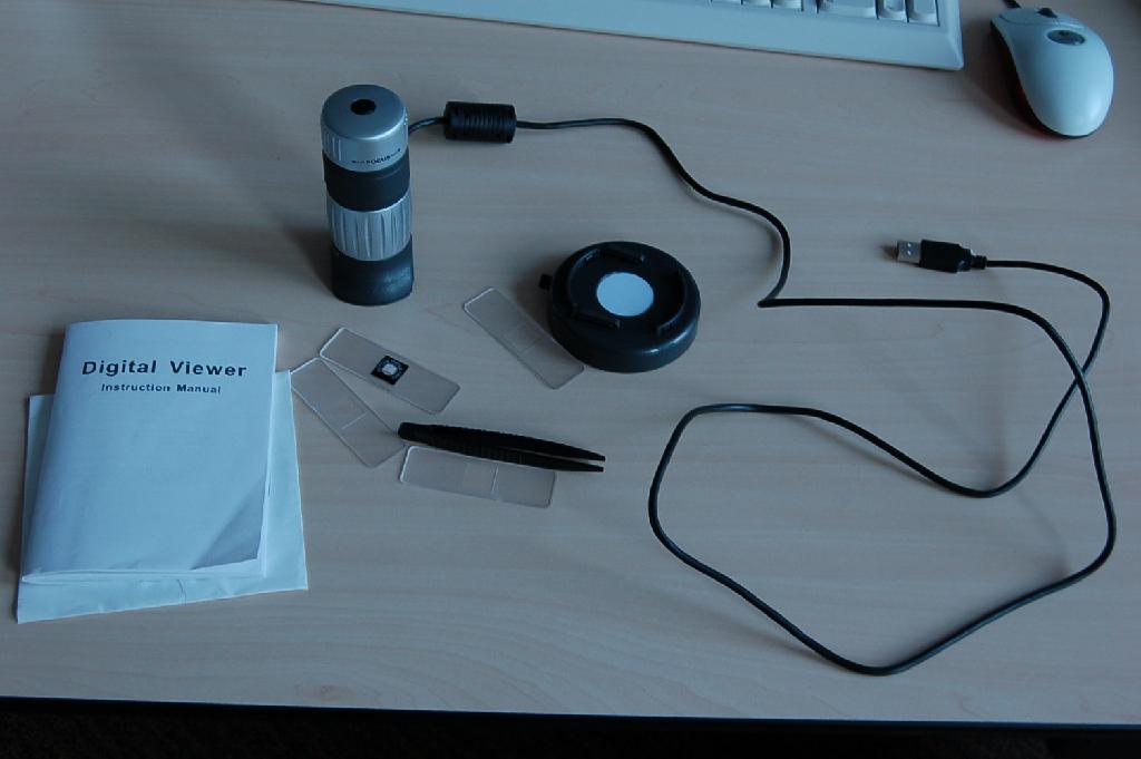 Een optische microscoop opgemaakt in een assortiment en bestaande uit:
- een “digital viewer” met onder meer de volgende kenmerken:
- een behuizing van kunststof;
- een sluiterknop aan de bovenzijde;
- een draaibare ring om scherp te stellen;
- een draaibare ring om in te zoomen;
- een lens met 5x optische zoom;
- een resolutie van 640 x 480 pixels;
- voorzien van een USB-kabel;
- afmetingen van 85,5 x 80 x 130 mm;
- een pincet van kunststof met een lengte van 10 cm;
- een viertal dekglaasjes van kunststof met afmetingen van ongeveer 
  70 x 20 mm;
- een druppelaar van kunststof met een lengte van 6,5 cm.
Het assortiment wordt aangeboden in een kartonnen doos tezamen met een installatie CD en een gebruiksaanwijzing en is opgemaakt voor de verkoop in het klein.