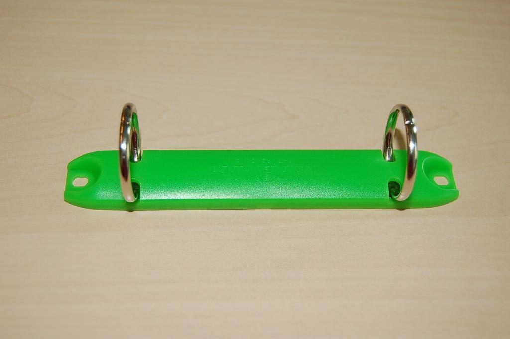 Een ringbandmechanisme voor opbergmappen van onedel metaal, in een behuizing van kunststof, met een lengte van ongeveer 12,2 cm, voorzien van vier armen van staaldraad. De armen zijn aan de onderzijde gemonteerd op twee rechthoekige stalen platen en kunnen worden gesloten door de twee tegenover elkaar liggende armen naar elkaar toe te drukken waardoor ze ringen vormen. De rechthoekige platen met uitsparingen, worden beschermd door een behuizing van kunststof voorzien van twee gaten om het mechanisme aan een opbergmap te bevestigen.