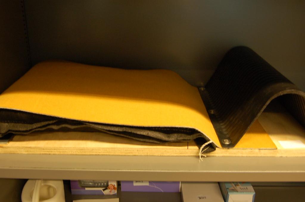 Een non woven vloerbedekking op rollen met een breedte van 115 cm, zijnde een zogenoemde "topcover" van een vloermatsysteem voor koeien, bestaande uit drie lagen:
- een gele geïmpregneerde slijtvaste toplaag van gebonden 
  textielvlies voorzien van een waslaag voor het eenvoudig reinigen;
- een witte tussenlaag van gebonden textielvlies van synthetische 
  textielvezels van polypropyleen;
- een zwarte onderlaag van weefsel van polypropyleen waardoor vezels
  afkomstig van het gebonden textielvlies heen steken.
De vloerbedekking wordt tezamen aangeboden met een koeienmatras en profielen waarvoor separaat BTI's zijn afgegeven onder de referentienummers NL-RTD-2008-000262, NL-RTD-2008-000380 en NL-RTD-2008-000381. De bovenzijde van gebonden textielvlies geïmpregneerd met was geeft aan het tapijt het wezenlijke karakter, waarbij er geen textielstof waarneembaar is. 
Deze BTI dient ter vervanging van de BTI met referentienummer NL-RTD-2008-000379.