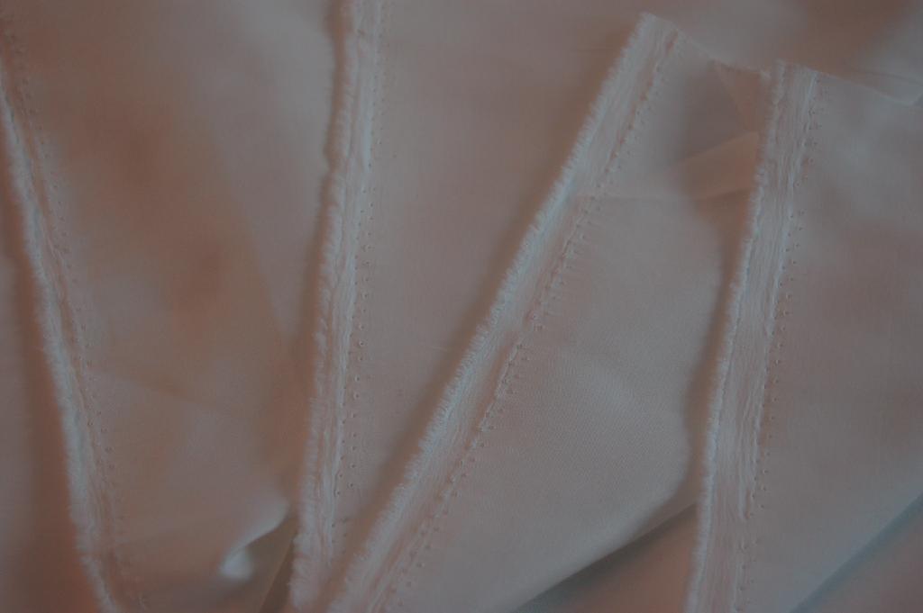 Een wit weefsel vervaardigd van meer dan 85% synthetische stapelvezels van polyester.