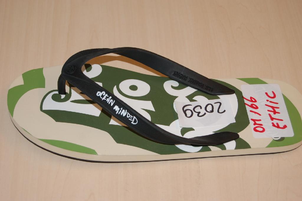 Een teenslipper met buitenzool en bovendeel van rubber of van kunststof. Het schoeisel waarvan het bovendeel uit riempjes bestaat die met pluggen in gaten in de zool zijn aangebracht, heeft onder andere de volgende kenmerken: 
- het bovendeel bestaat uit een V-vormige kunststof band dat aan weerszijden van de voet en ter hoogte van de tenen (met pluggen) in de zool is bevestigd; 
- een platte geprofileerde buitenzool van rubber;
- voorzien van merknaam en/of logo op het bovendeel en het voetbed.