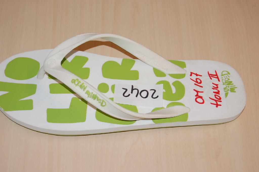 Een teenslipper met buitenzool en bovendeel van rubber of van kunststof. Het schoeisel waarvan het bovendeel uit riempjes bestaat die met pluggen in gaten in de zool zijn aangebracht, heeft onder andere de volgende kenmerken: 
- het bovendeel bestaat uit een V-vormige kunststof band dat aan weerszijden van de voet en ter hoogte van de tenen (met pluggen) in de zool is bevestigd; 
- een platte geprofileerde buitenzool van rubber;
- voorzien van merknaam en/of logo op het bovendeel en het voetbed.