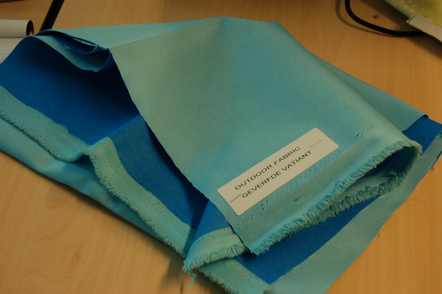 Een weefsel van meer dan 85 gewichtsprocenten niet–getextureerde synthetische textielfilamenten van polyester.
Een zijde van het weefsel is lichtblauw, de andere zijde is donkerblauw. 
Er is geen deklaag met het blote oog zichtbaar.
Het weefsel wordt aangeboden –volgens opgave- op rollen met een breedte van ongeveer 150 cm en een lengte van ongeveer 30 meter.