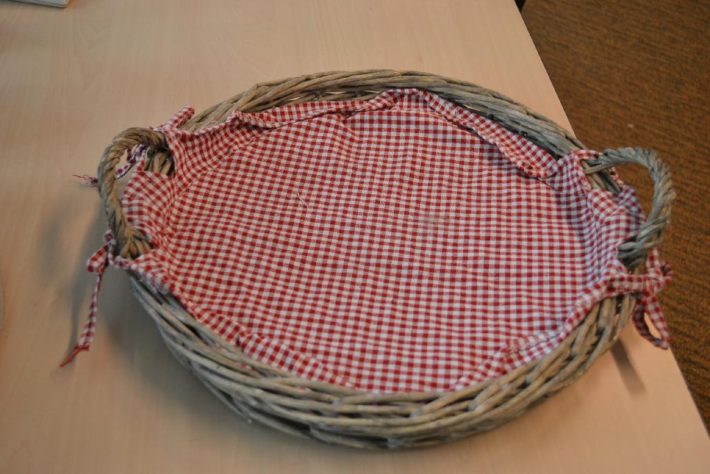 Mandenmakerswerk vervaardigd van vlechtwerk, zijnde een dienblad met een deksel, met onder meer de volgende kenmerken:
- volgens opgave- van rotting;
- voorzien van 2 draaghengsels;
- een doorsnede van ongeveer 40 cm;
- afgedekt met een geruite doek die vastgemaakt is aan de hengsels;
- het deksel heeft een metalen frame;
- het deksel heeft een doorsnede van ongeveer 33 cm;
- het geheel heeft een hoogte van ongeveer 17 cm;
- aan de bovenzijde voorzien van een handvat.